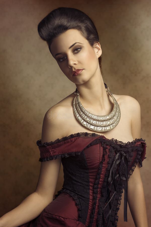 Portrait of beautiful young woman in elegant old fashion purple dress , and a very importatnt necklace. hairdo. Portrait of beautiful young woman in elegant old fashion purple dress , and a very importatnt necklace. hairdo.