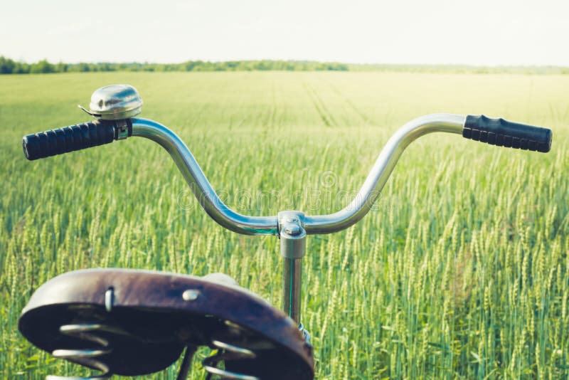 Винтажный handlebar с колоколом на велосипеде Летний день для отключения Взгляд пшеничного поля напольно closeup стоковая фотография rf Винтажный handlebar с колоколом на велосипеде Летний день для отключения Взгляд пшеничного поля напольно closeup стоковая фотография rf