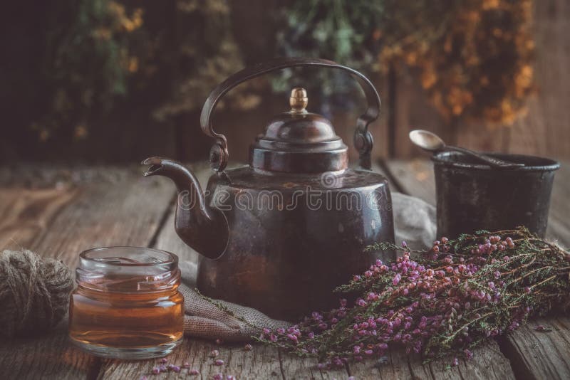 Винтажный чайник, чашка чаю, опарник меда, пук вереска и целебные пачки трав на предпосылке стоковые изображения rf Винтажный чайник, чашка чаю, опарник меда, пук вереска и целебные пачки трав на предпосылке стоковые изображения rf