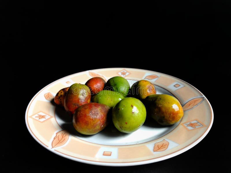 Вкусные jocotes на тарелке с черным фоном Плоды, родившиеся в Центральной Америке