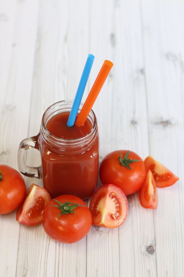 Вкусный томатный сок в стакане и свежие помидоры на светло-сером столе стоковое изображение rf