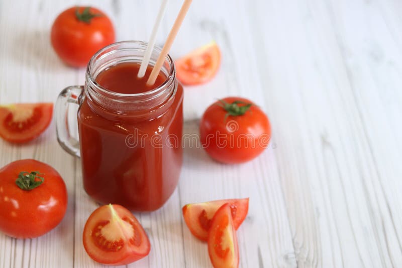 Вкусный томатный сок в стакане и свежие помидоры на светло-сером столе стоковое изображение