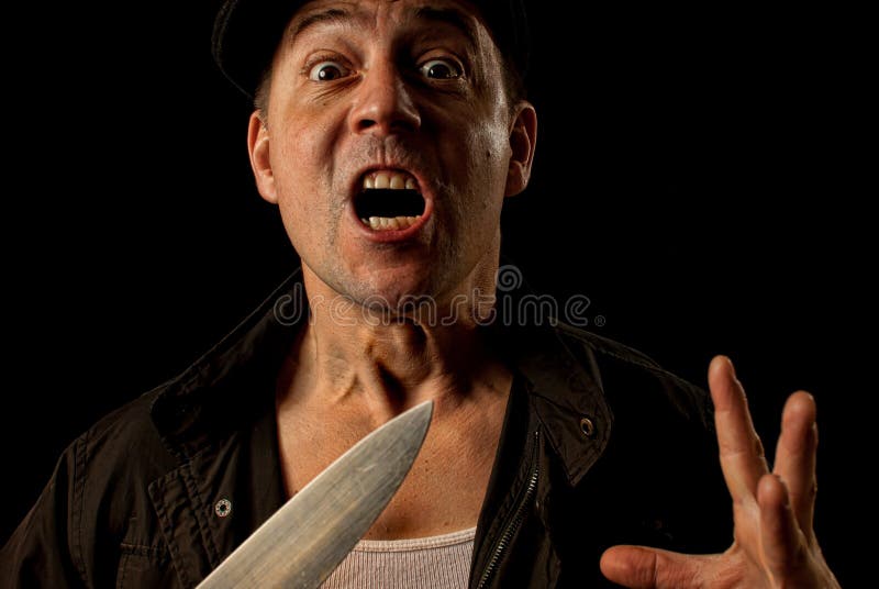 A crazed angry knife wielding maniac criminal mugger on a black background. A crazed angry knife wielding maniac criminal mugger on a black background