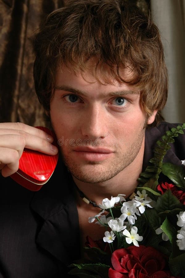 A handsome man offering candy in a heart shaped box and flowers. A handsome man offering candy in a heart shaped box and flowers