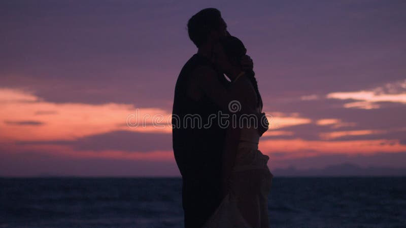 влюбленный нежно обнимает свою девушку на закате на море. влюбленная пара. романтическая пара