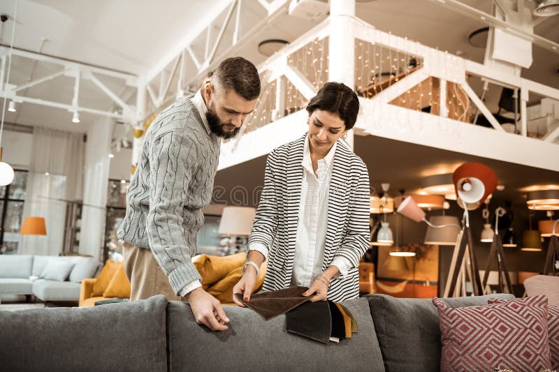 Внимательный бородатый темн-с волосами человек смотря на части ткани стоковое фото rf