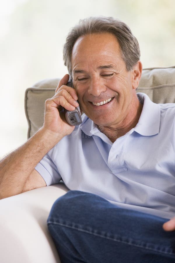Man indoors using telephone smiling. Man indoors using telephone smiling.