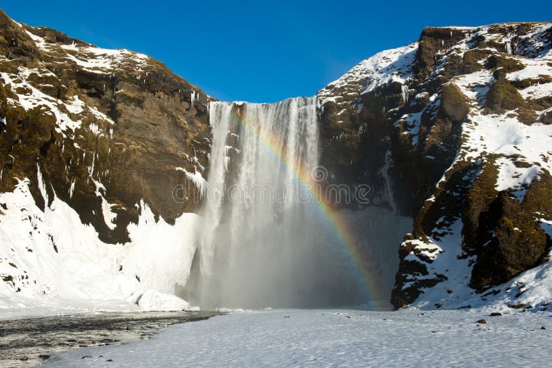 Водопад Skogafoss зимы с снегом и радугой, Исландией стоковые изображения Водопад Skogafoss зимы с снегом и радугой, Исландией стоковые изображения