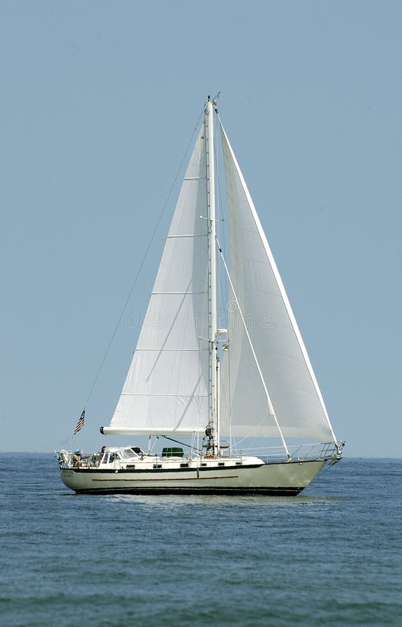 A white sailboat with sails deployed, on the ocean. crop is vertical. A white sailboat with sails deployed, on the ocean. crop is vertical.