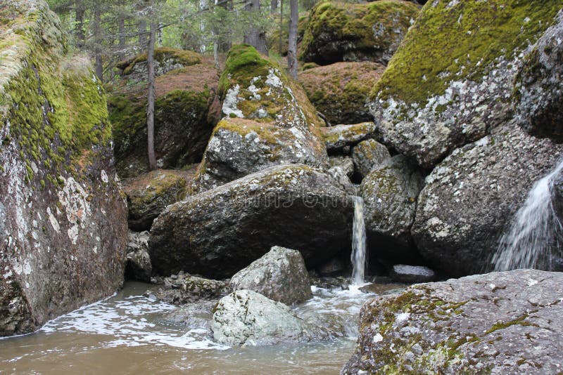 Водопад горной реки протекает через русло реки через огромные валуны с moss стоковое фото rf