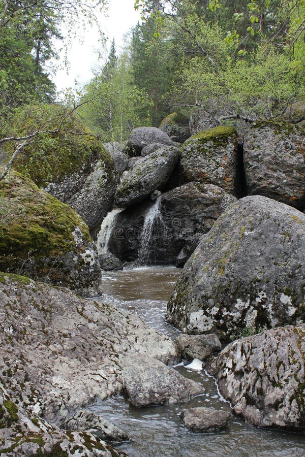 Водопад горной реки протекает через русло реки через огромные валуны с moss стоковая фотография rf
