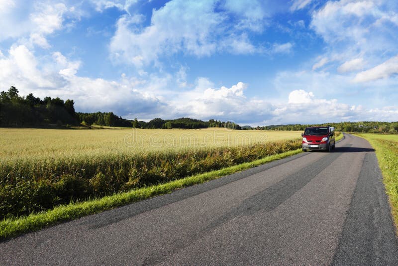 Car, suv, driving along on a lonely, straight narrow country-road, summer, green fields and meadows. sweden. Car, suv, driving along on a lonely, straight narrow country-road, summer, green fields and meadows. sweden