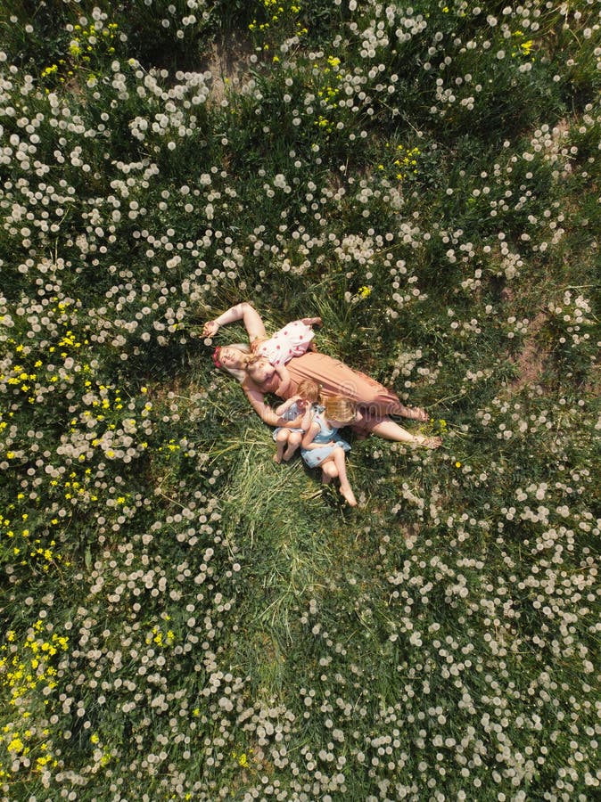 Mother having quality funny playing time with her baby girls at a park blowing dandelion - Young blonde hippie - Daughters wear similar dresses with strawberry print - Family values - 1, 2, 6 year old children on a sunny spring day. Mother having quality funny playing time with her baby girls at a park blowing dandelion - Young blonde hippie - Daughters wear similar dresses with strawberry print - Family values - 1, 2, 6 year old children on a sunny spring day