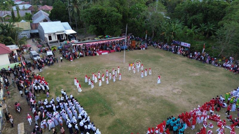 Aerial view of Indonesian flag lowering ceremony witnessed by villagers. Indonesia Independence Day. Aerial view of Indonesian flag lowering ceremony witnessed by villagers. Indonesia Independence Day.
