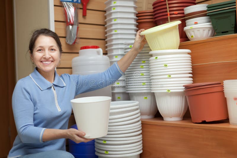 Mature woman chooses a flower pot in the store for gardeners. Mature woman chooses a flower pot in the store for gardeners