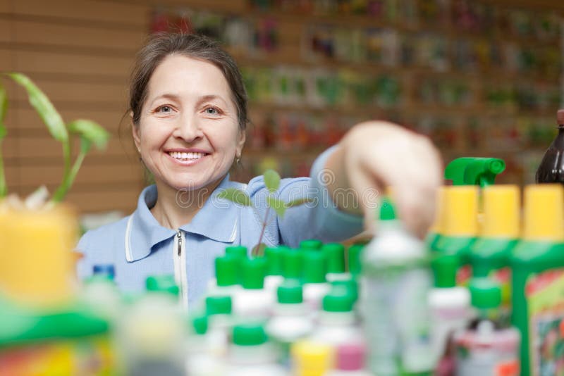 Female mature gardener chooses liquid fertilizer at store for gardeners. Female mature gardener chooses liquid fertilizer at store for gardeners