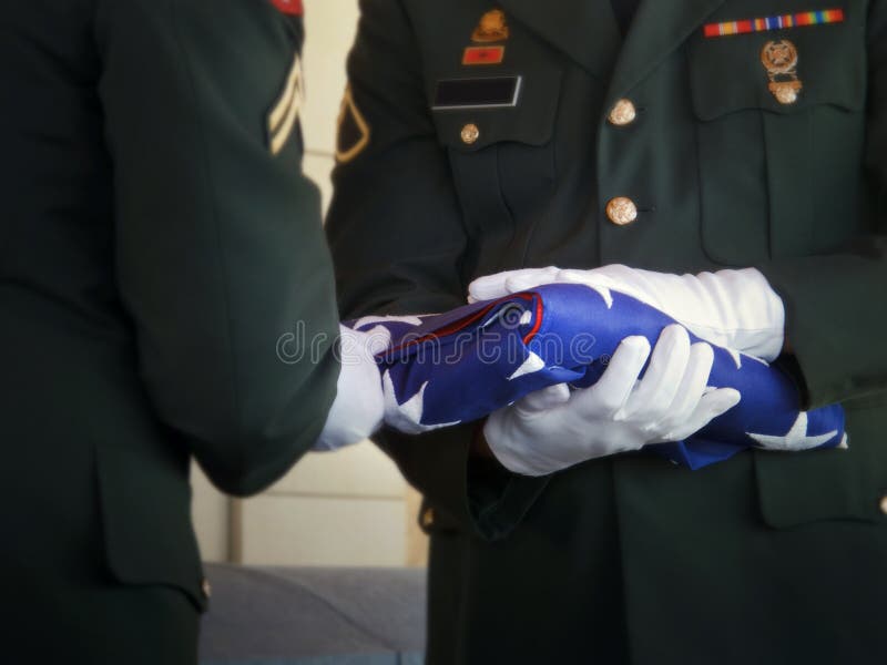 This military honor guard carefully folds the United States flag for presentation to family members at a veterans funeral. Selective focus on flag and gloved hands. Would make good illustration for U.S. Veterans Day, U.S. Memorial Day or honoring military service. This military honor guard carefully folds the United States flag for presentation to family members at a veterans funeral. Selective focus on flag and gloved hands. Would make good illustration for U.S. Veterans Day, U.S. Memorial Day or honoring military service.