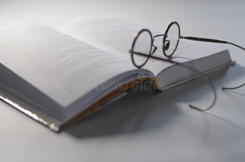 Вокруг старых стекел положите на открытую белую книгу, которая лежит на белой предпосылке стоковая фотография rf Вокруг старых стекел положите на открытую белую книгу, которая лежит на белой предпосылке стоковая фотография rf