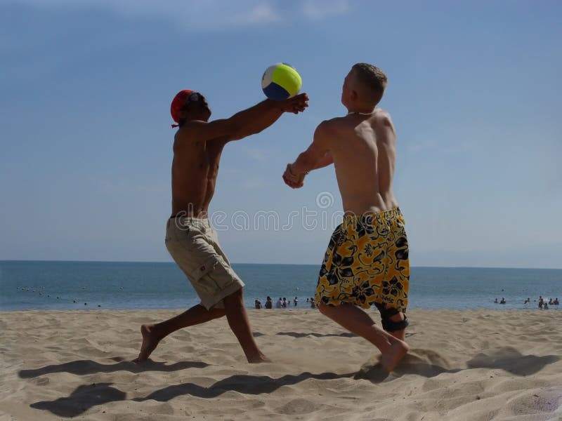 2 men playing volleyball on the beach. 2 men playing volleyball on the beach