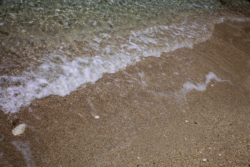 Волнистый пенообразный кристалл - ясная вода океана моя вверх на береге песчаного пляжа Белизна развевает на песке ослабляя время стоковая фотография Волнистый пенообразный кристалл - ясная вода океана моя вверх на береге песчаного пляжа Белизна развевает на песке ослабляя время стоковая фотография