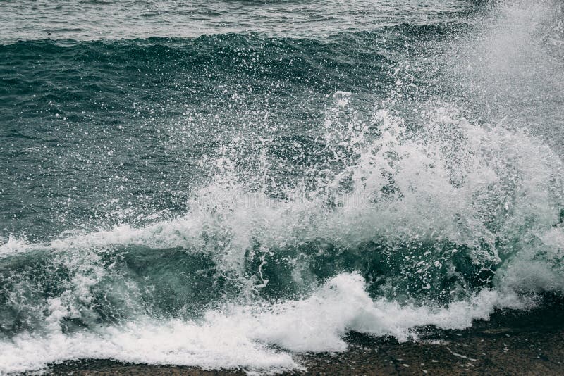 Волны моря брызгают на береговой линии, бурной морской воде с движением пены стоковые фото