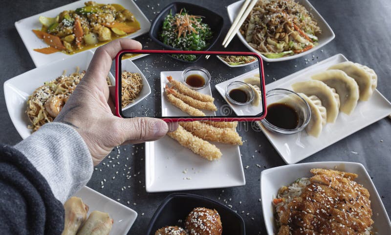 Восточная кухня. мужчина фотографирует свои смартфонные тарелки с рисовой лапшой.. блог продуктов стоковая фотография rf
