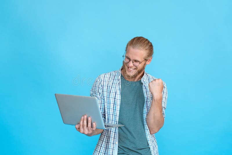 Excited happy rejoicing businessman student hipster glasses hold modern pc laptop yes victory win gesture raise fist smile at screen read text email online isolated blue studio background copy space. Excited happy rejoicing businessman student hipster glasses hold modern pc laptop yes victory win gesture raise fist smile at screen read text email online isolated blue studio background copy space.