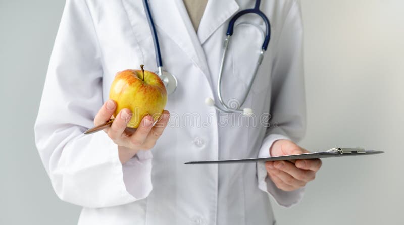 Doctor holding healthy fruit, improve health. A woman with a manicure holding a green apple in her hands. Doctor holding healthy fruit, improve health. A woman with a manicure holding a green apple in her hands