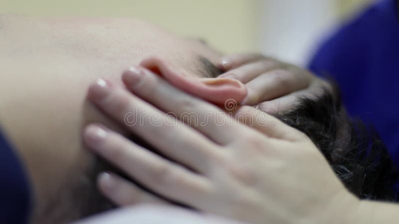 врач-остеопат держит руку на голове возле уха акции видеоматериалы