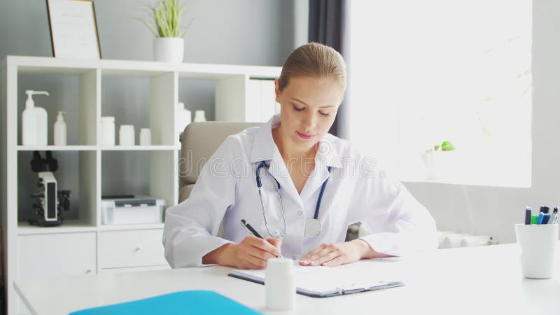 врач работает в медицинском учреждении. женщина в белом пальто. работа профессионального терапевта-женщины в больнице или акции видеоматериалы