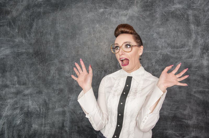 Scared teacher in the eyeglasses on the blackboard background. Scared teacher in the eyeglasses on the blackboard background