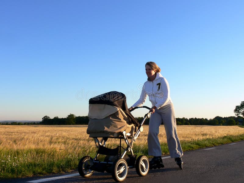 A mother inlining on a countryroad with a pram and baby. A mother inlining on a countryroad with a pram and baby