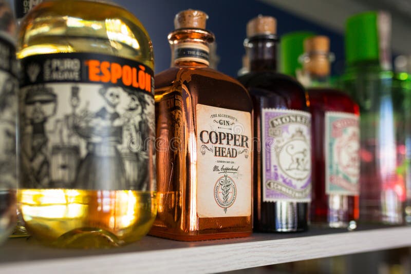 Gdansk, Poland - May 24, 2018: Selection of alcohol bottles on the bar shelf. Selective focus on the Copper Head gin bottle. Gdansk, Poland - May 24, 2018: Selection of alcohol bottles on the bar shelf. Selective focus on the Copper Head gin bottle.