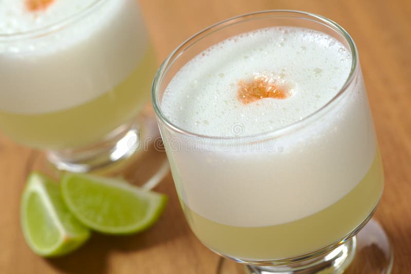 Peruvian cocktail called Pisco Sour made of Pisco (Peruvian grape schnaps), lime juice, syrup, egg white, and some angostura (bitter fluid) drops on top (Selective Focus, Focus on the front of the angostura). Peruvian cocktail called Pisco Sour made of Pisco (Peruvian grape schnaps), lime juice, syrup, egg white, and some angostura (bitter fluid) drops on top (Selective Focus, Focus on the front of the angostura)