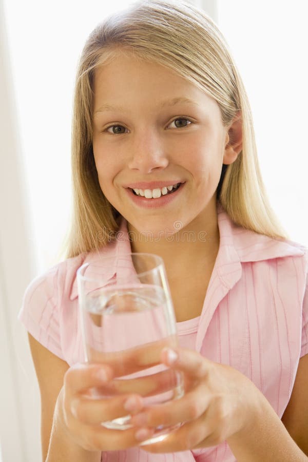 Portrait of girl drinking glass of water indoors by a window. Portrait of girl drinking glass of water indoors by a window