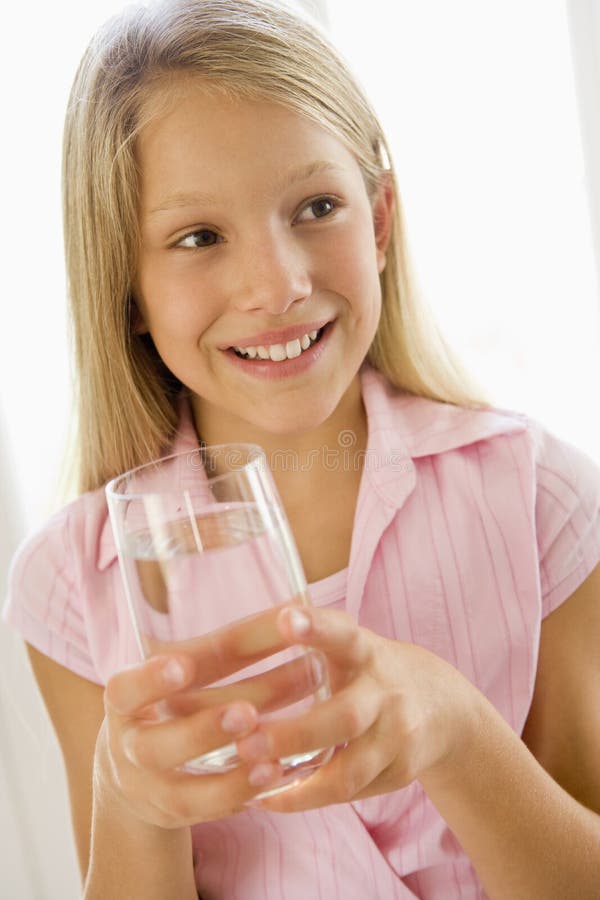 Portrait of girl drinking glass of water indoors by a window. Portrait of girl drinking glass of water indoors by a window