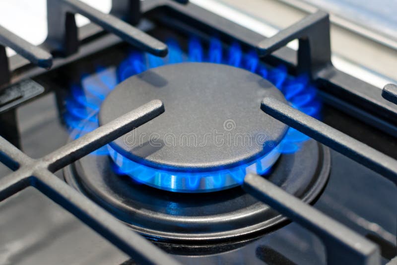 Газовая горелка горит с голубым пламенем на плите под защитным грилем стоковая фотография Газовая горелка горит с голубым пламенем на плите под защитным грилем стоковая фотография