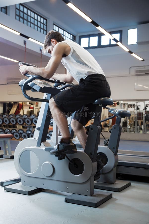 Portrait of young man bicycling in gym. Portrait of young man bicycling in gym.