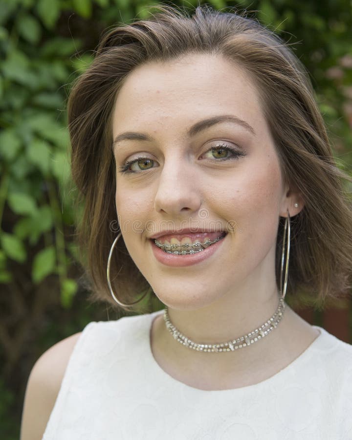 Pictured is a fifteen year-old teenage girl before her first school dance. She is smiling anticipating a fun night. She has pierced ears, braces, and medium length brown hair. Pictured is a fifteen year-old teenage girl before her first school dance. She is smiling anticipating a fun night. She has pierced ears, braces, and medium length brown hair.