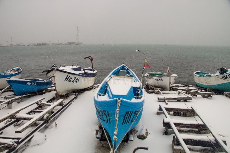 Голубая шлюпка, идет снег белизна и Чёрное море в Pomorie, Болгарии стоковые изображения