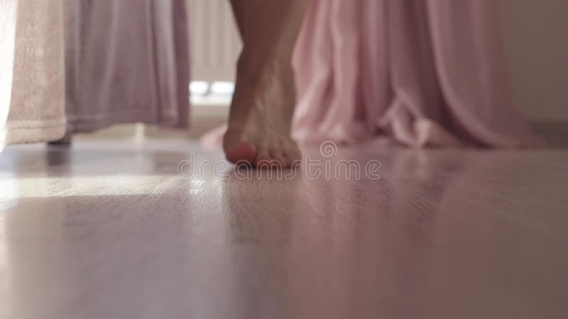 голые ноги женщины ходят по полу от окна к камере. закрыть женский босой ступень на теплый деревянный пол