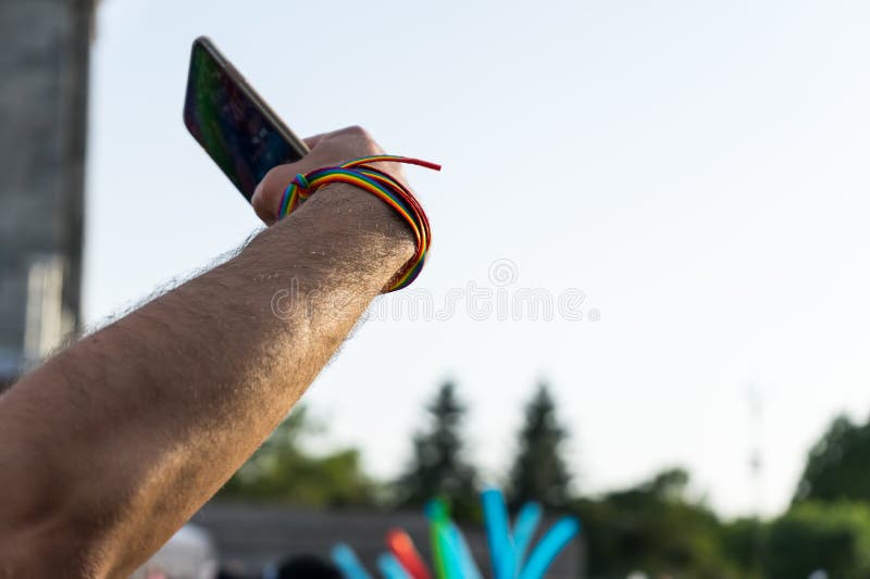 гомосексуальный молодой человек с wristband радуги, браслетом и умным телефоном принимая selfie в фестивале гордости стоковое изображение rf гомосексуальный молодой человек с wristband радуги, браслетом и умным телефоном принимая selfie в фестивале гордости стоковое изображение rf