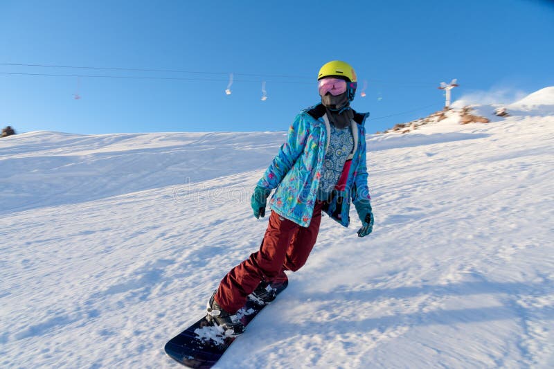 ГОРА ELBRUS, РОССИЯ - 30-ОЕ НОЯБРЯ 2017: Девушка сноуборда нося маску солнца и шарф едет вниз с высокогорного стоковое изображение rf ГОРА ELBRUS, РОССИЯ - 30-ОЕ НОЯБРЯ 2017: Девушка сноуборда нося маску солнца и шарф едет вниз с высокогорного стоковое изображение rf
