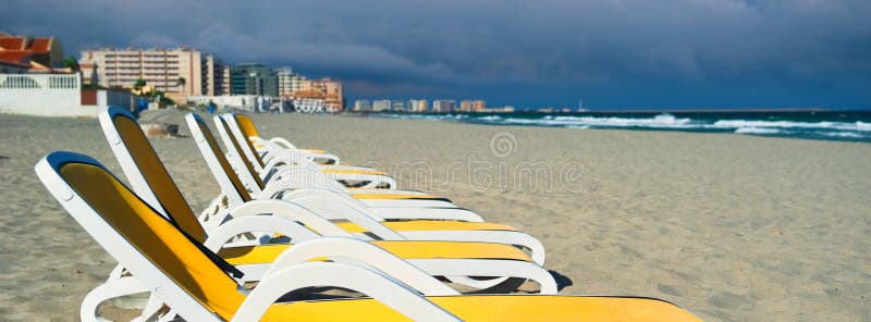 Горизонтальное изображение подрезало шезлонги sunbeds желтого голубого цвета взгляда пустые в ряд на песчаном пляже, Ла Manga Del стоковая фотография
