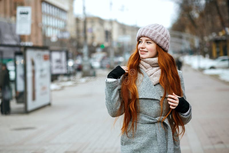 Городской портрет великолепной девушки redhead с длинными волосами нося w стоковые изображения Городской портрет великолепной девушки redhead с длинными волосами нося w стоковые изображения