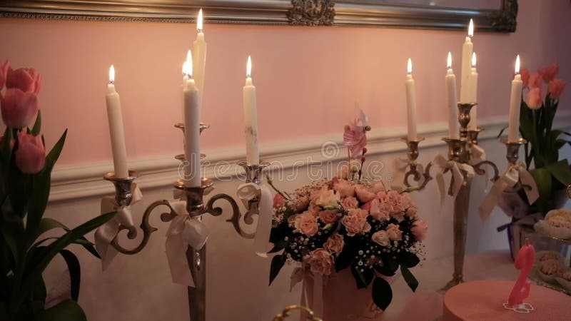 Горящие свечи, букеты цветков на таблице в зале банкета