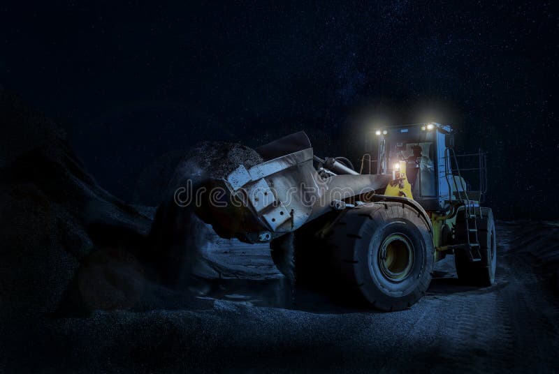 Гравий затяжелителя колеса черпая на строительном проекте nighttime стоковые изображения Гравий затяжелителя колеса черпая на строительном проекте nighttime стоковые изображения