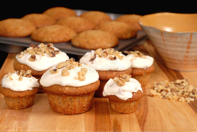 Frosted banana walnut muffins with chopped nuts and full muffin pan. Frosted banana walnut muffins with chopped nuts and full muffin pan