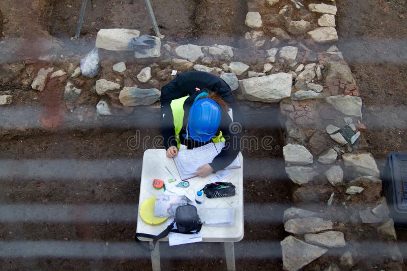 Thessaloniki, Greece. October 2016. A female archaeologist making notes on a fenced-off dig site in Greece. Thessaloniki, Greece. October 2016. A female archaeologist making notes on a fenced-off dig site in Greece.