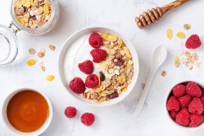 Греческий йогурт в шаре с полениками, медом и muesli на белом каменном взгляде столешницы Завтрак здорового питания стоковое изображение rf Греческий йогурт в шаре с полениками, медом и muesli на белом каменном взгляде столешницы Завтрак здорового питания стоковое изображение rf